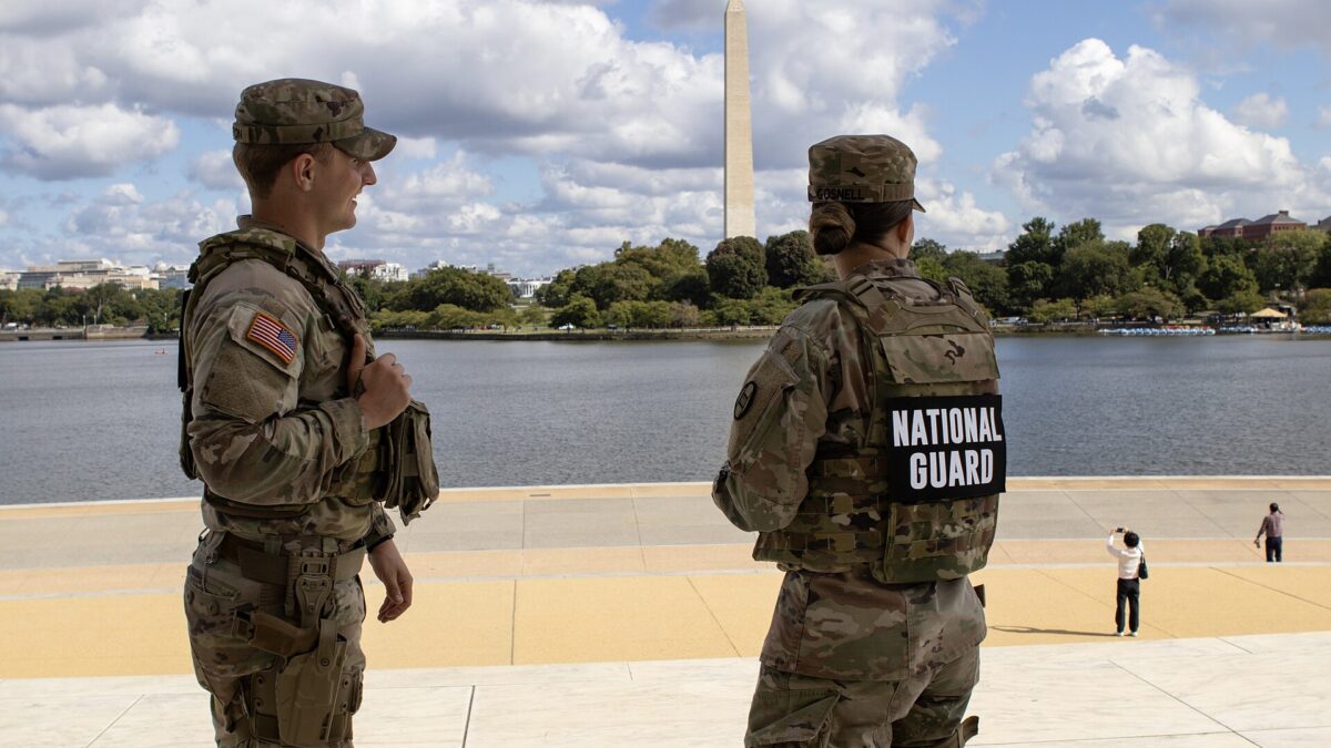Two National Guard members stand watch near the Tidal Basin with the Washington Monument behind them