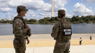 Two National Guard members stand watch near the Tidal Basin with the Washington Monument behind them