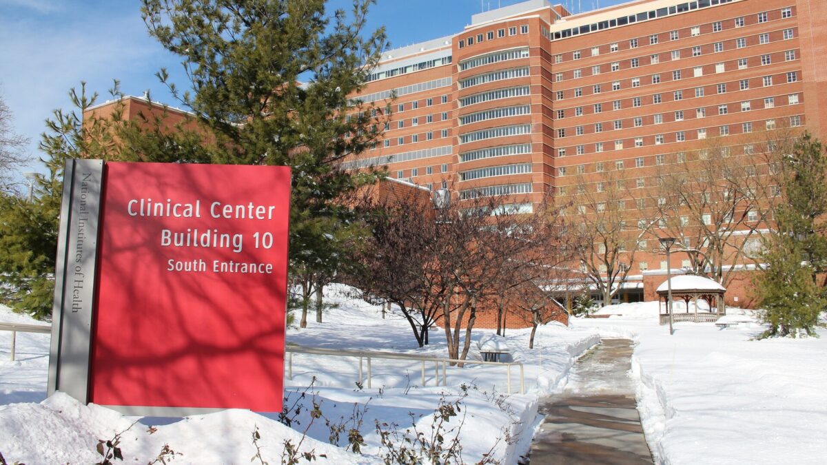 Red sign at the south entrance of the NIH Clinical Center, Building 10, in Bethesda, Maryland, with snow on the ground