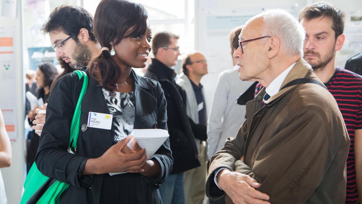 French chemist Henri Kagan speaking with a young researcher at a 2013 organic chemistry conference held in his honor at École Polytechnique