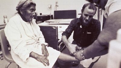 A physician treating an elderly patient in a hospital room