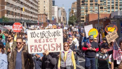 Demonstrators march with signs at an October 2025 No Kings rally in New York City