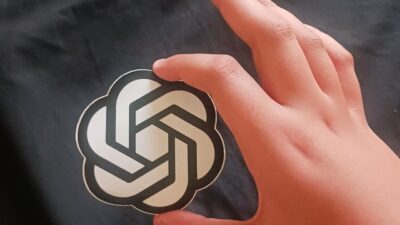 A hand holding a card with the OpenAI logo
