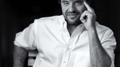Black-and-white portrait of Stanford neuroscientist Karl Deisseroth seated in a wooden chair