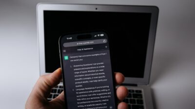 A smartphone displaying the ChatGPT app resting beside a laptop