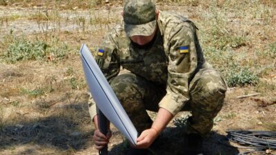A Ukrainian soldier sets up a Starlink satellite internet terminal in a field