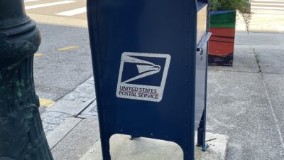 Blue U.S. Postal Service collection box on a city street