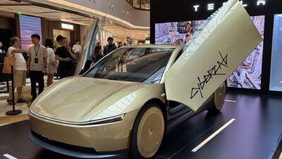 A gold-colored Tesla Cybercab with its doors open on display in a shopping mall